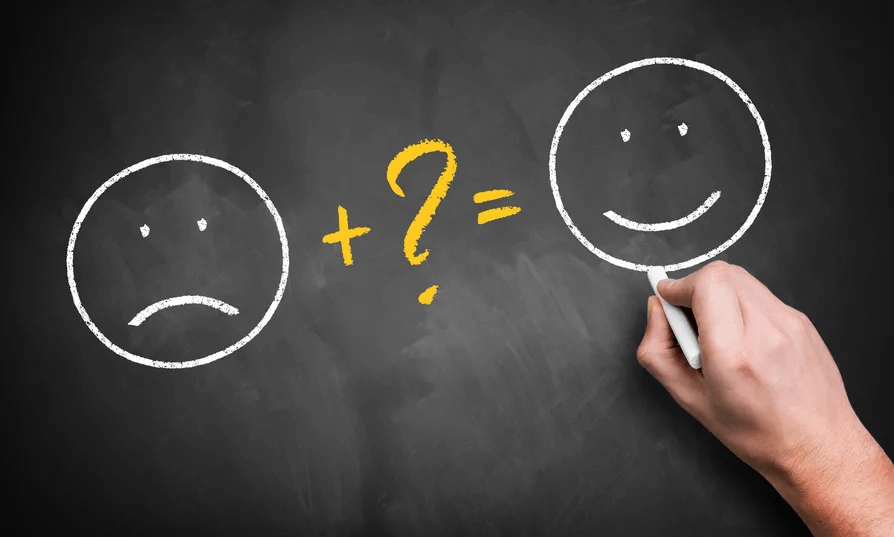 Eine auf eine Tafel gezeichnete Formel: Ein trauriger Smiley plus ein Fragezeichen ergeben sich glücklichen Smiley