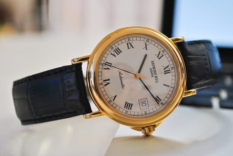 A gold and black wristwatch lies on a table